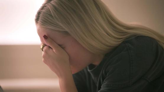 A blonde woman with her face in her hands.