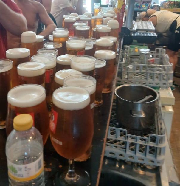 Many pints of beer on a bar.