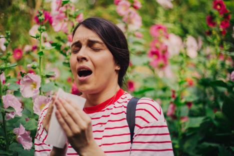 Woman sneezing in a flower garden.