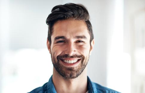 Portrait of a smiling young man in a denim shirt.