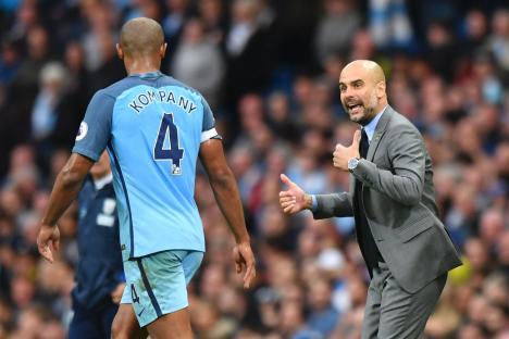 Pep Guardiola giving instructions to Vincent Kompany during a soccer match.